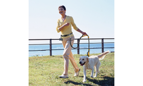 Laisse Chien Mains Libres Femme courant avec un chien utilisant une laisse rétractable orange mains libres, ceinture réglable, poignées rembourrées.